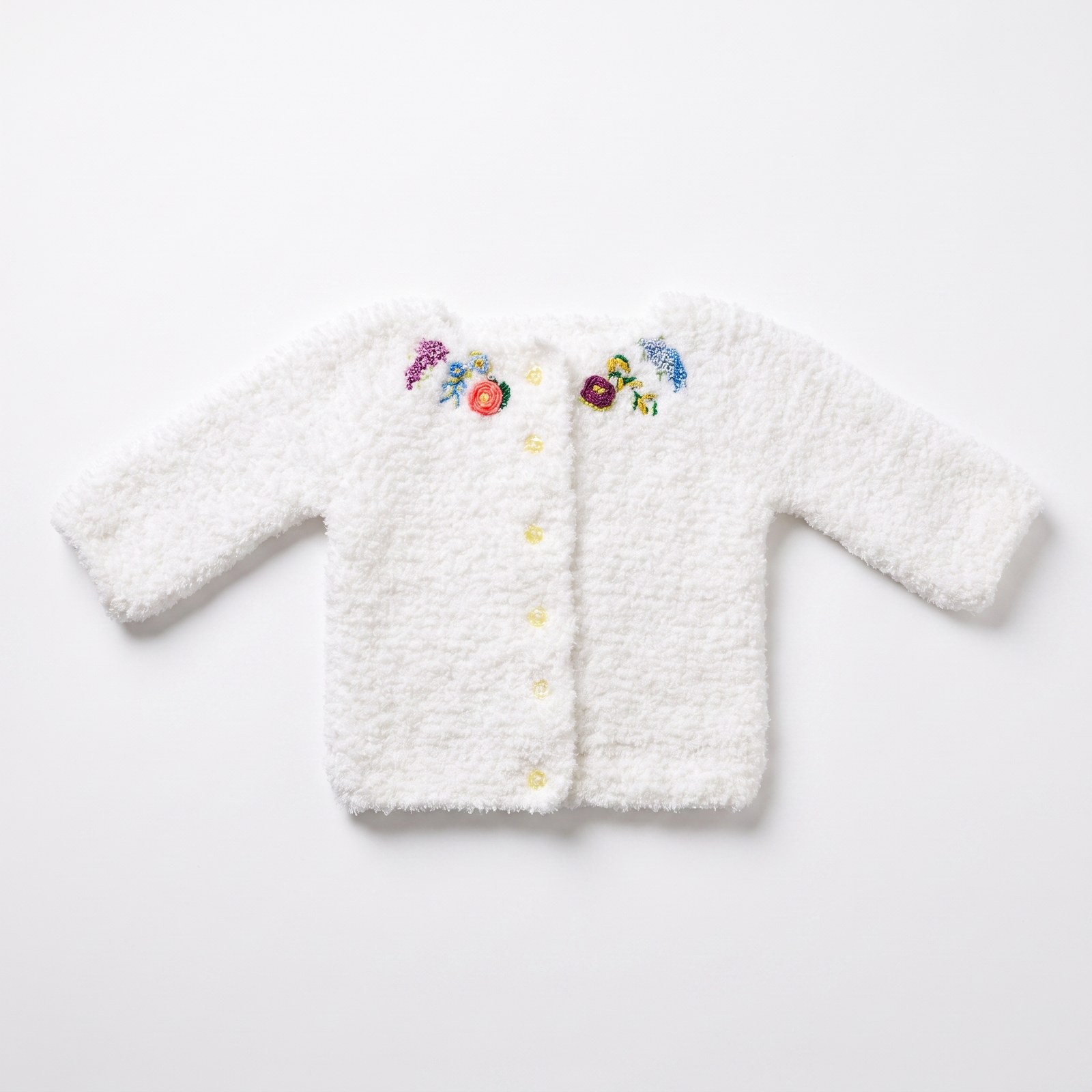 White fluffy hand-knit baby cardigan and matching headband with multi-coloured embroidered flowers at the shoulders