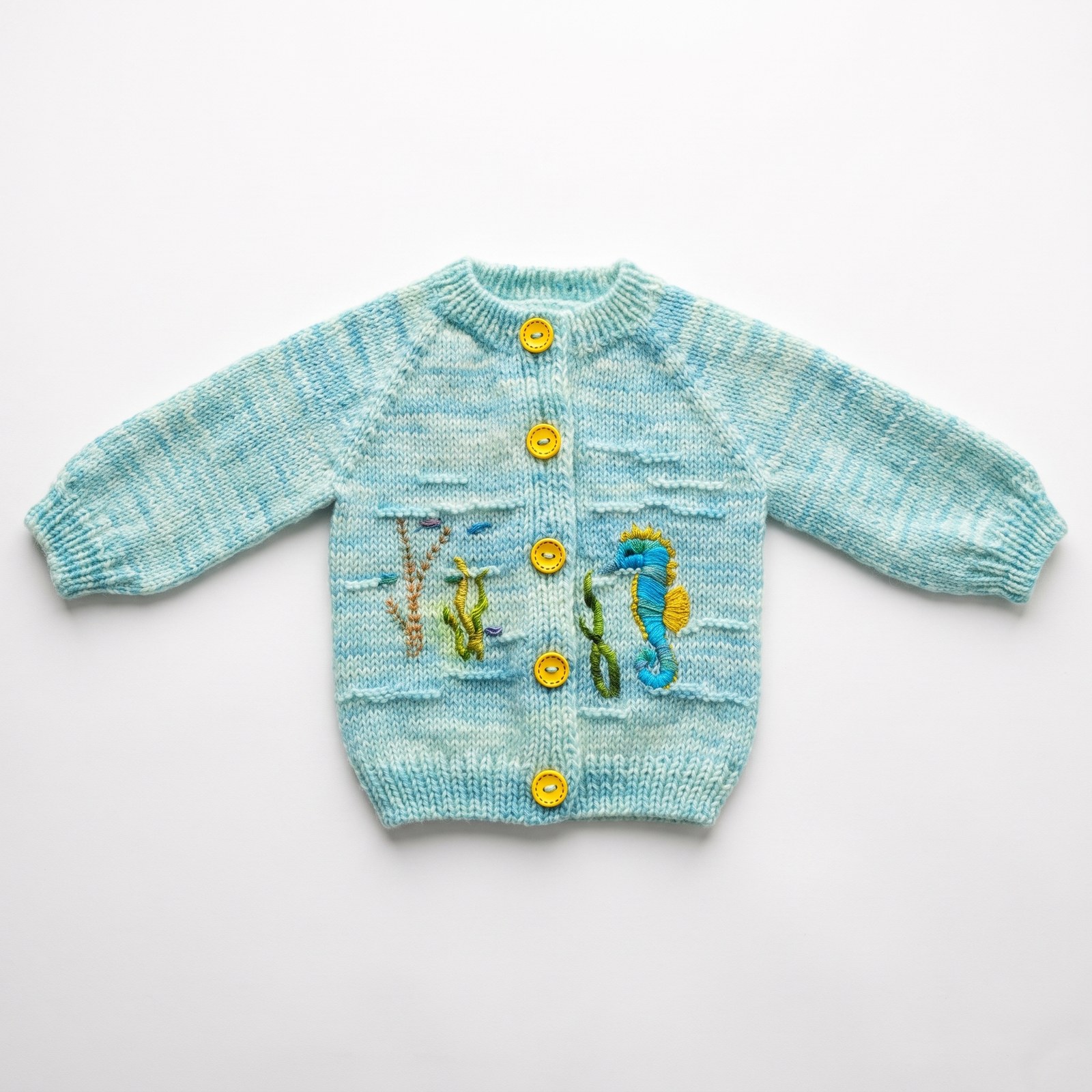 Aqua hand-knit baby cardigan with embroidered seahorse and seaweed, yellow buttons